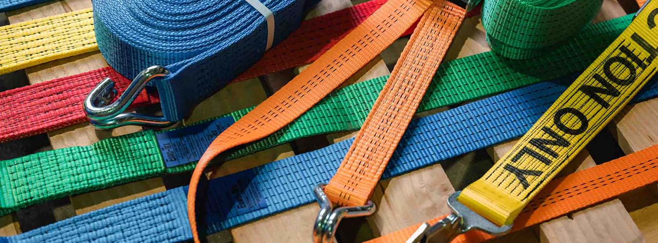 red, blue and orange taut straps fastened and lying next to each other with silver hardware